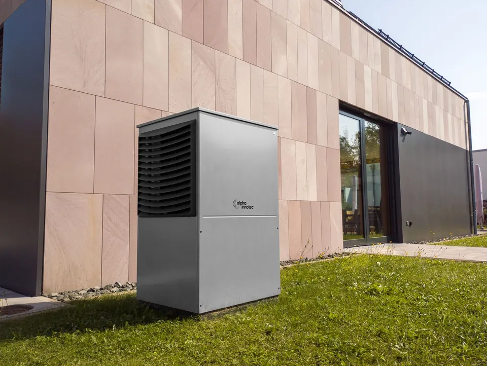 Buitenunit van een warmtepomp naast een woning