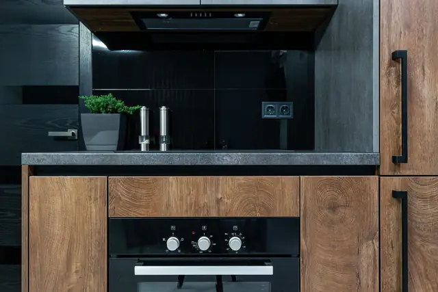 Keuken met houten kastfronten, zwarte details en inbouwapparatuur