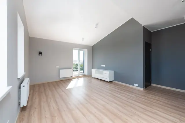Lege, opgeleverde woonkamer met lichte wanden en houten vloer