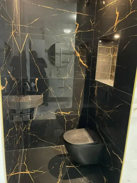 Toilet met zwart-gouden marmerlook tegels en verlichte nis