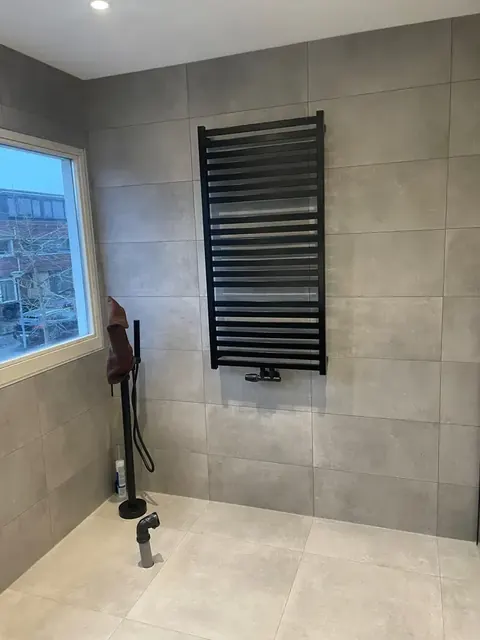 Dezelfde badkamer tijdens de afbouw: radiator en douche aangesloten, nog zonder glazen wand