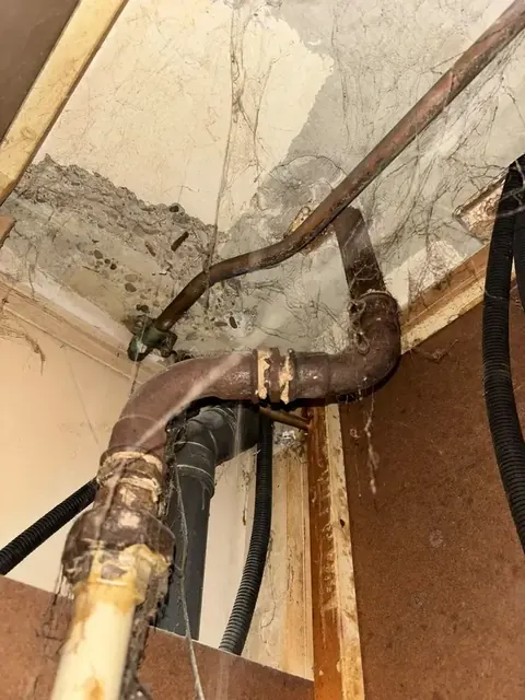 Oude leidingen achter een weggehaalde wand